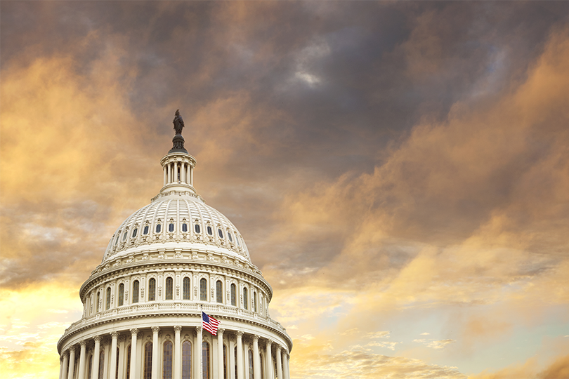 Photo of the United States Capitol rotunda with a cloudy sky in the background