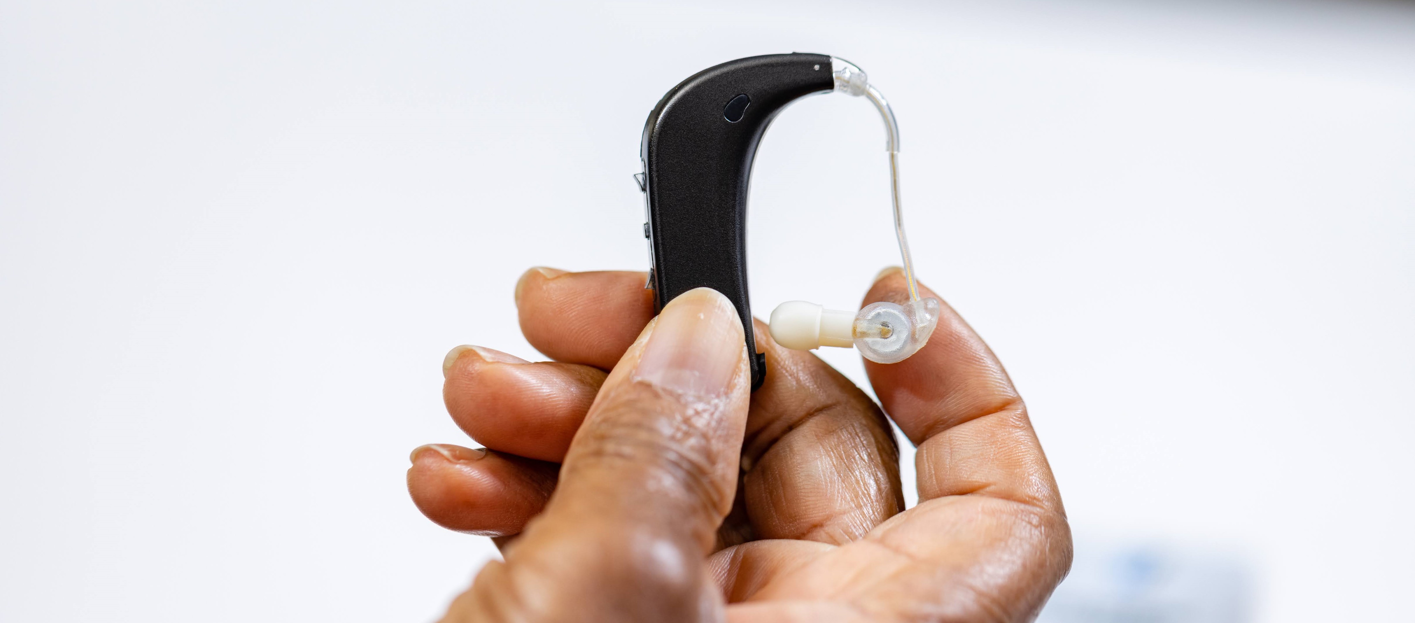 A hand holds an over-ear amplification device