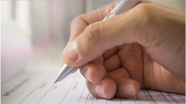 a right hand holding a pen over paper