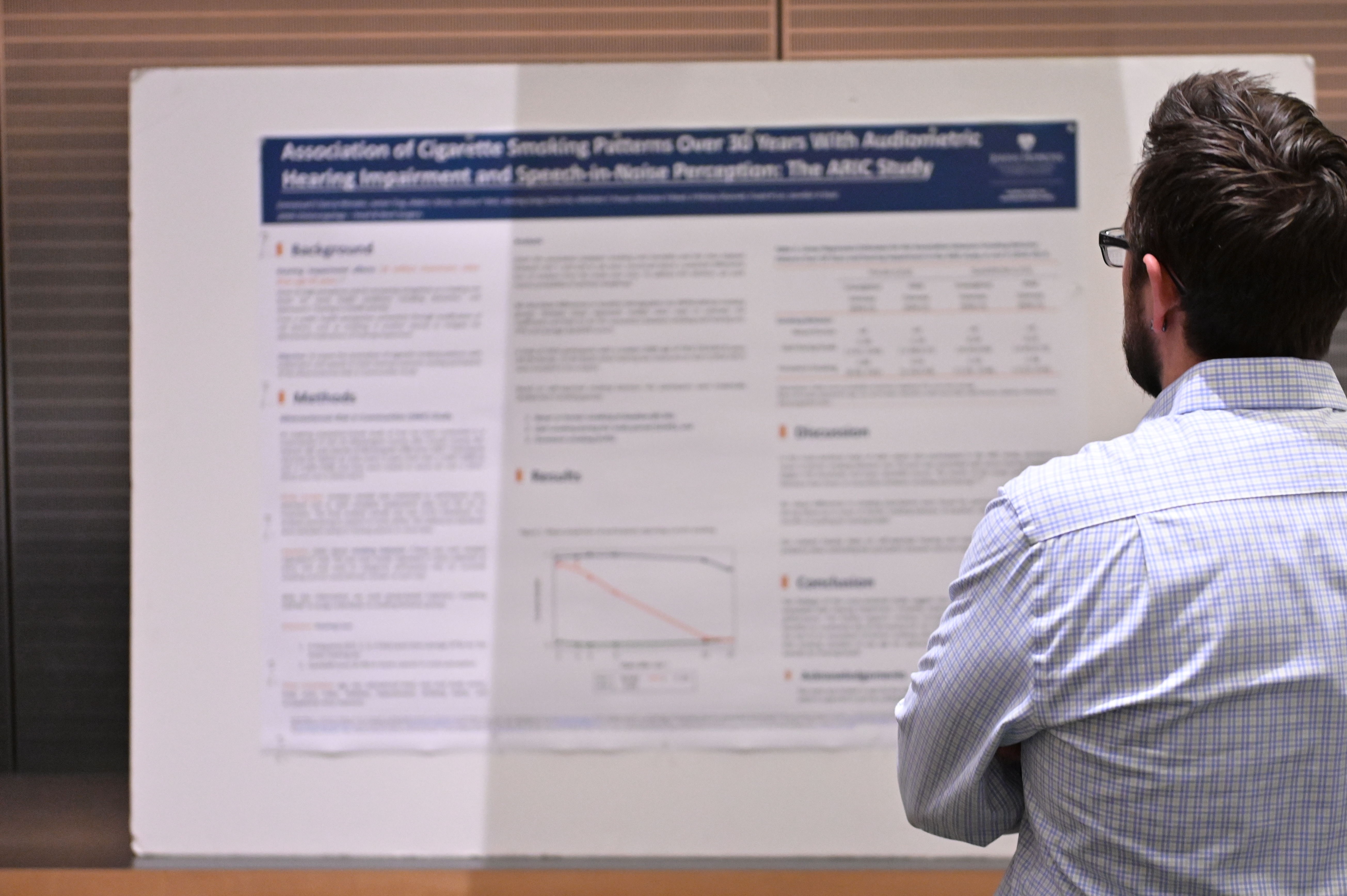 An attendee at 2023 Cochlear Center Research Day reads a poster.
