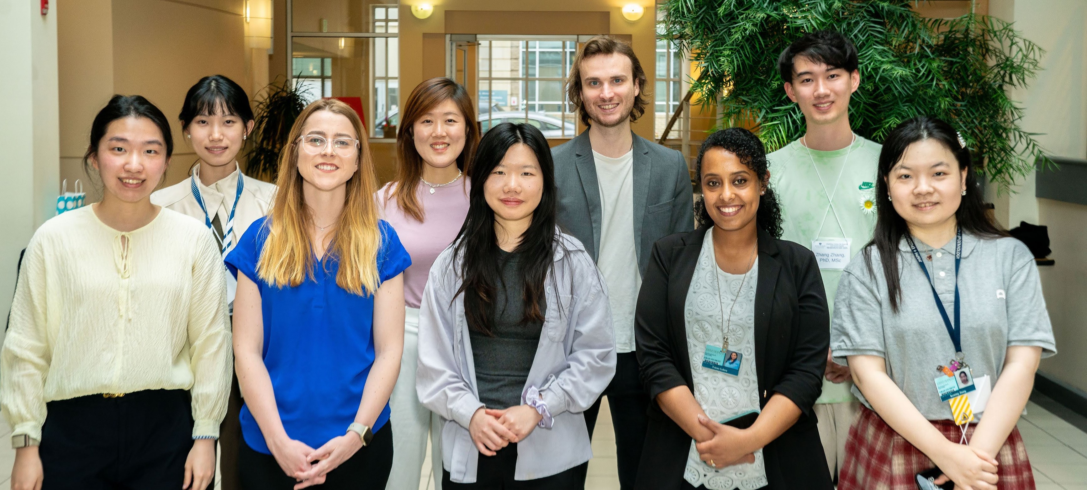 Cochlear Center trainees and others pose in a group shot in a sunny atrium.