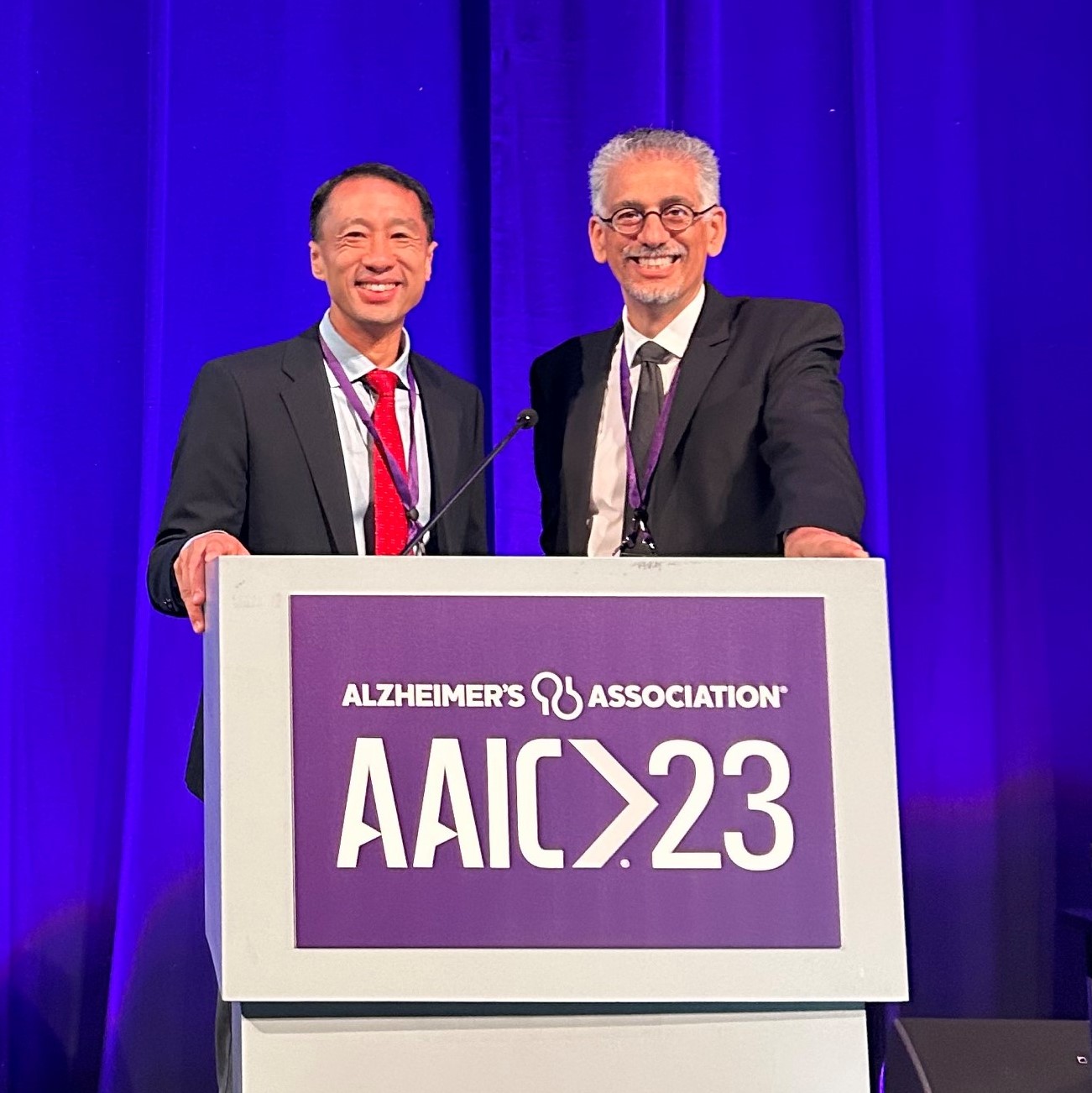 Frank Lin and Joe Coresh behind a podium ahead of presenting ACHIEVE study results