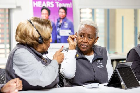 Two CHWs on the HEARs project demonstrate how to fit a hearing aid