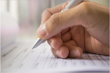 a right hand holding a pen over paper