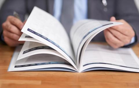 A pair of hands flips through pages of an open book